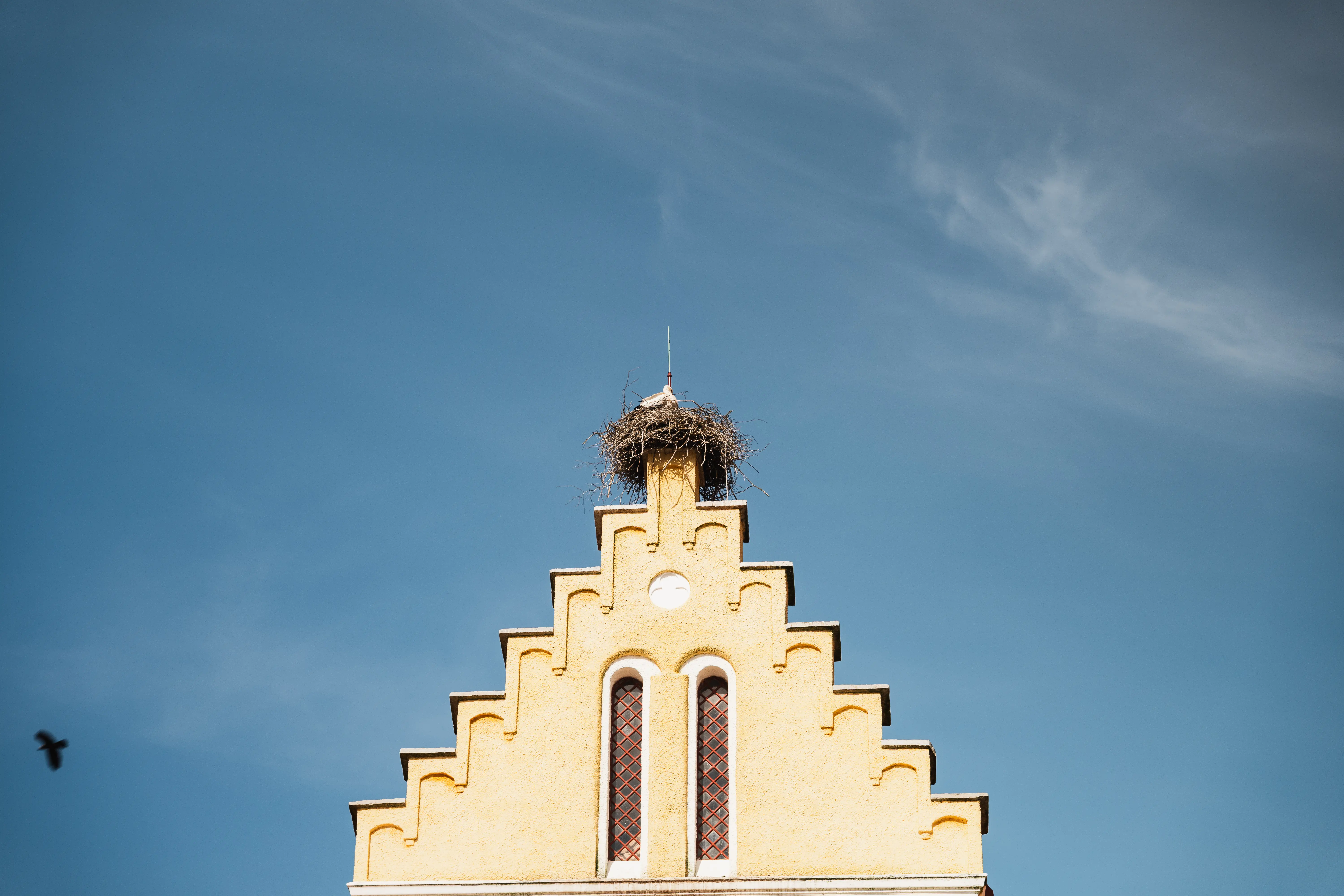 Trappstegshusgavel med storkbo på toppen och en blå himmel